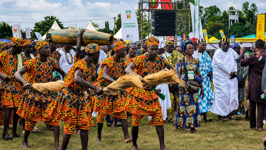 Danseurs traditionnels en tenue kente avec balais et tambours